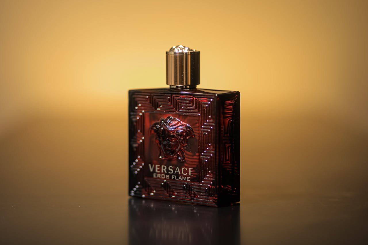 Close-up of Versace Eros Flame perfume bottle with a warm yellow backdrop.